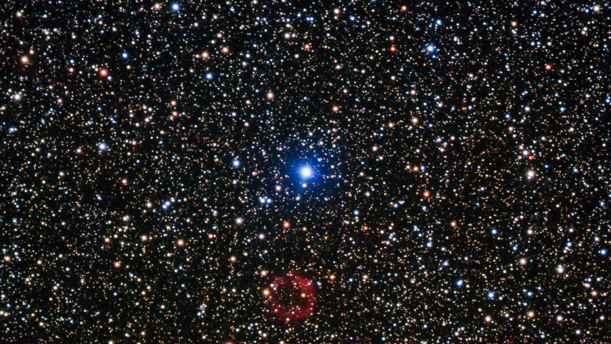 The bright star in the centre of this image is not the star of this show. At the bottom centre is a rather unremarkable smudge of red which is in fact a rare and valuable object. First discovered by amateur Japanese astronomer, Yukio Sakurai, in 1996, and noted as a nova-like object, Sakurai’s discovery turned out to be far more interesting than the supernova he initially supposed it to be. The object is actually a small white dwarf star undergoing a helium flash — one of only a handful of examples of such an event ever witnessed by astronomers. Normally, the white dwarf stage is the last in the life cycle of a low-mass star. In some cases, however, the star reignites in a helium flash and expands to return to a red giant state, ejecting huge amounts of gas and dust in the process, before once again shrinking to become a white dwarf. It is a dramatic and short-lived series of events, and Sakurai’s Object has allowed astronomers a very rare opportunity to study the events in real time. The white dwarf emits sufficient ultraviolet radiation to illuminate the gas it has expelled, which can just be seen in this image as the ring of red material. This image was taken using the FORS instrument, mounted on ESO’s Very Large Telescope.